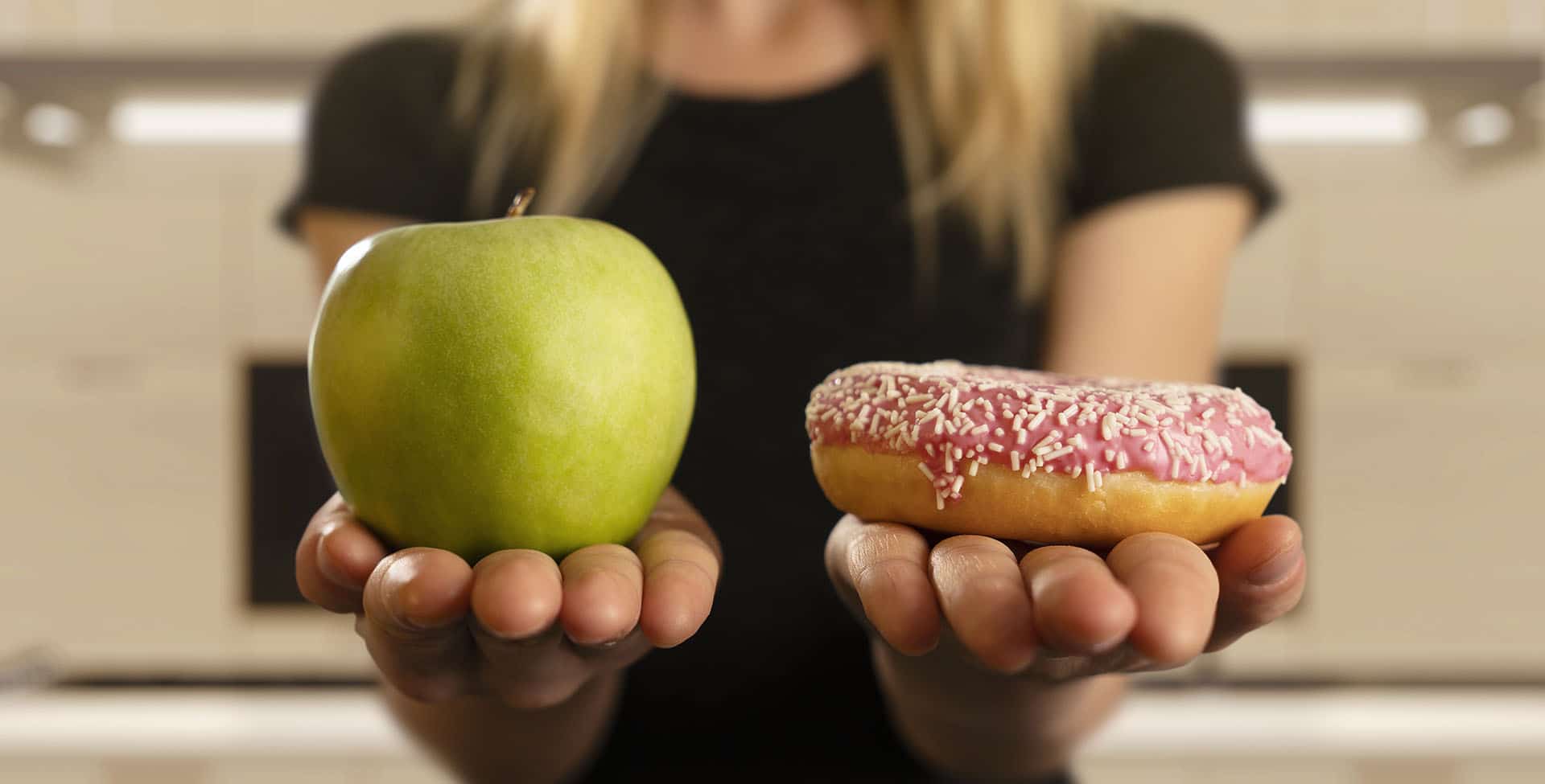 mulher compara uma maçã com um doce, um em cada mão