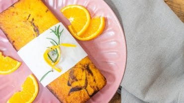 bolo de laranja mesclado servido em um prato rosa com rodelas de laranja