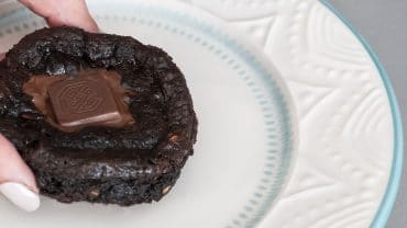 petit gateau fit em um prato branco, segurado por uma mão feminina