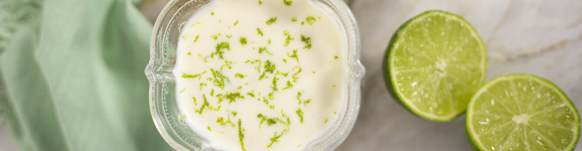 taça de sobremesa sob a mesa com mousse de limão, e um limão cortado ao lado