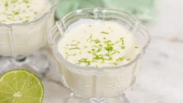 taça de sobremesa sob a mesa com mousse de limão, e um limão cortado ao lado