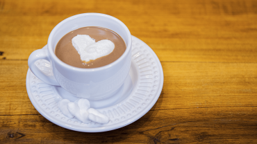 marshamallow caseiro mergulhado em uma xícara de chocolate quente.