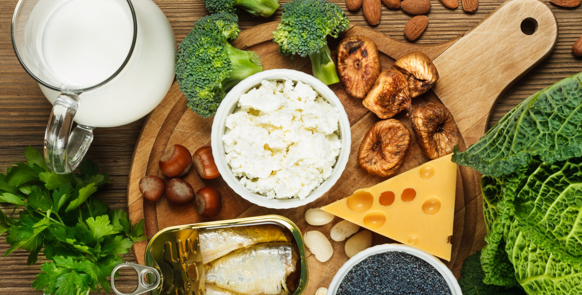 Alimentos ricos em cálcio em uma tábua de madeira em cima de uma mesa.