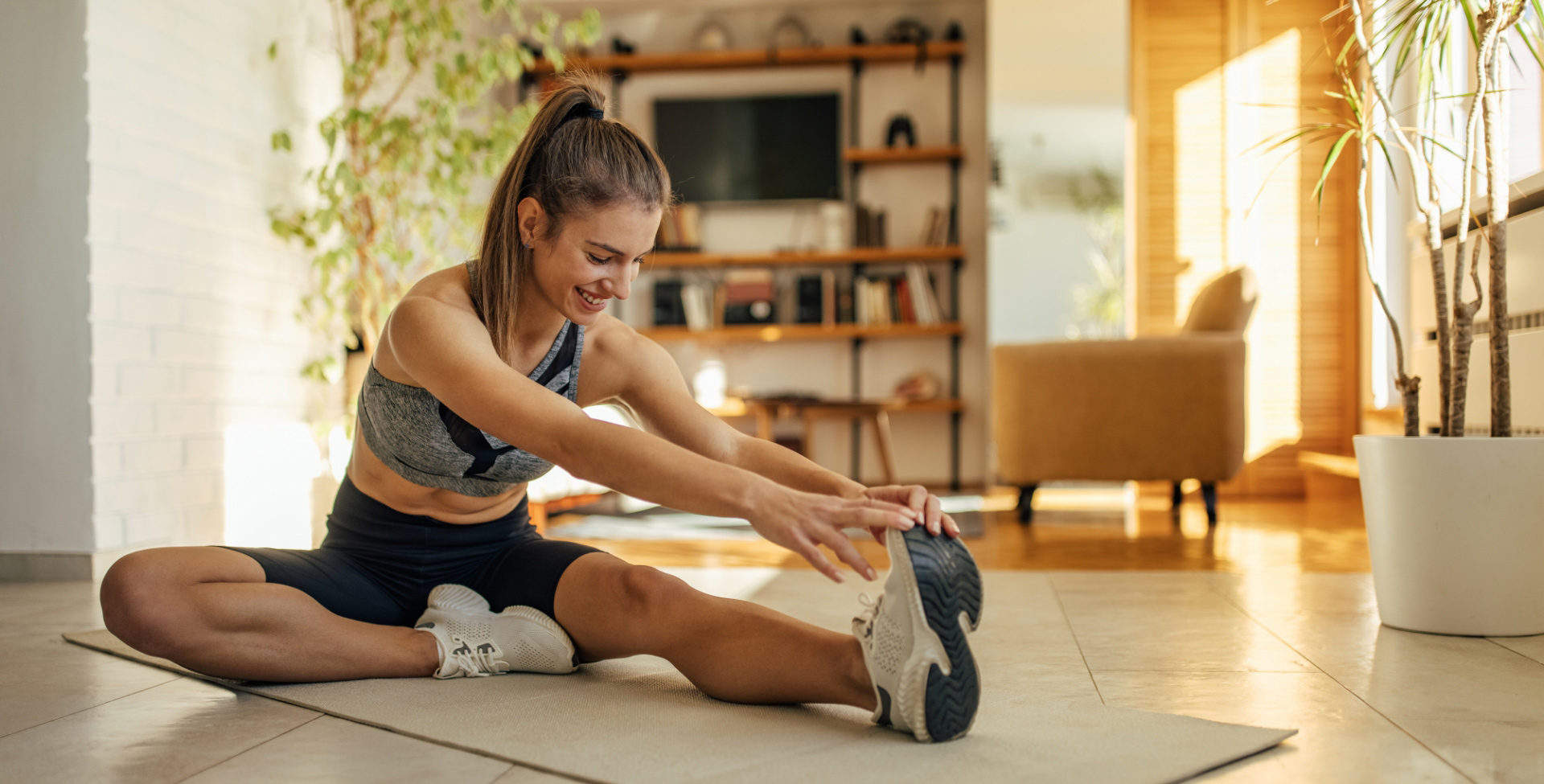 Mulher com tope, bermuda e tênis, realizando alongamento e aproveitando a flexibilidade que o colágeno proporciona para os ossos.